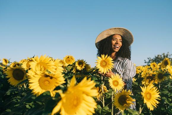Follow up health and nutritional consultations to ensure goals are being met. Woman enjoying life in a sunflower field.